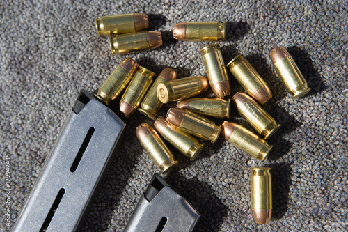 Photo Closeup of gun magazines and bullets on grey carpet