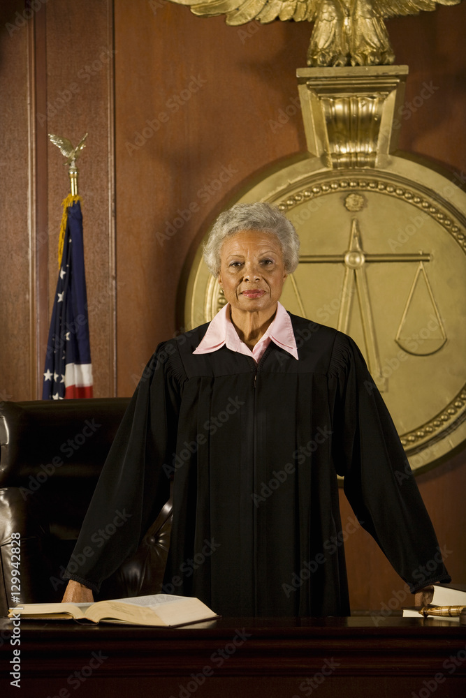 Portrait of confident senior female judge standing in court room Stock