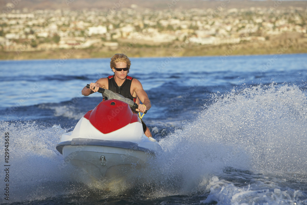 Young Caucasian man riding personal watercraft on lake Young Caucasian man riding personal watercraft on lake