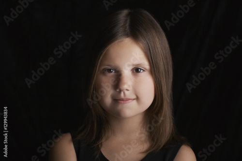 Closeup portrait of happy little girl on black background © moodboard