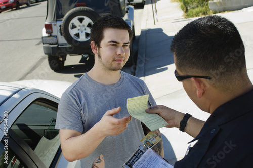 Police officer giving ticket to young man for breaking traffic rules