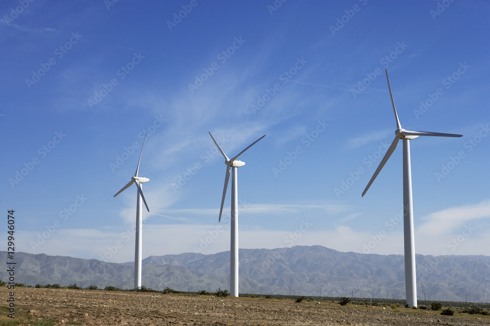 Three wind turbines in desert against blue sky Three wind turbines in desert against blue sky