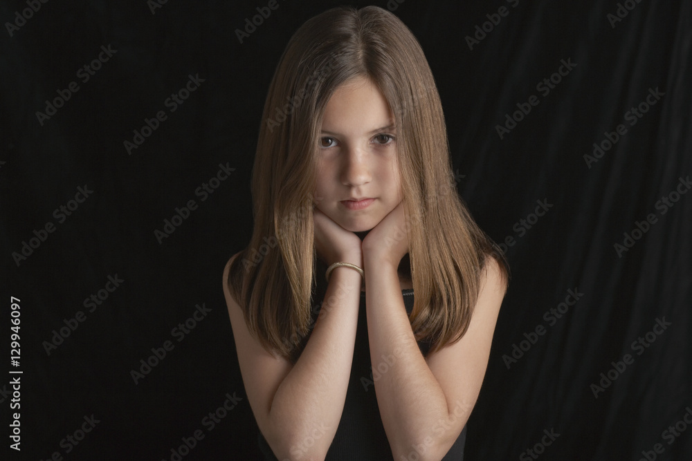 Portrait of young brunette girl resting chin in hands against black background Portrait of young brunette girl resting chin in hands against black background