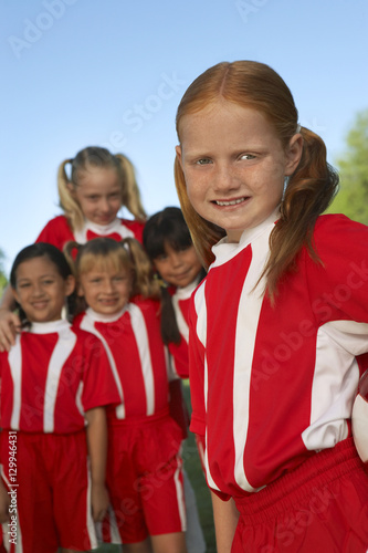 Portrait of girl soccer player with teammates in the background