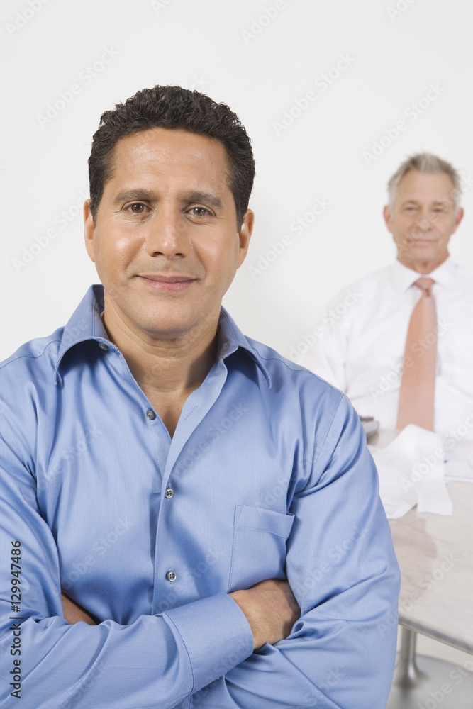 Portrait of a confident businessman with male colleague in background Portrait of a confident businessman with male colleague in background