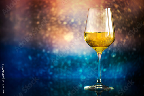 glass of white wine against a glowing bokeh - copy space  select
