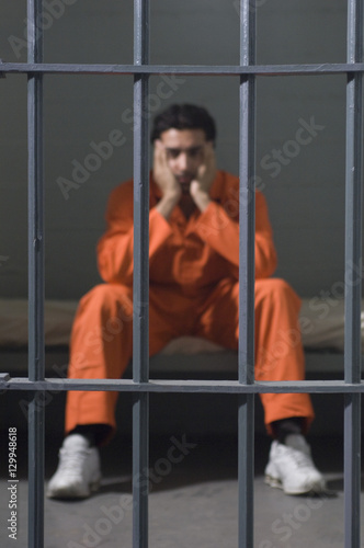 Depressed criminal sitting in prison cell