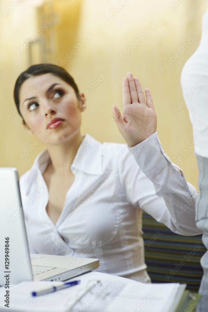 Young business woman showing stop gesture to her colleague in office Young business woman showing stop gesture to her colleague in office
