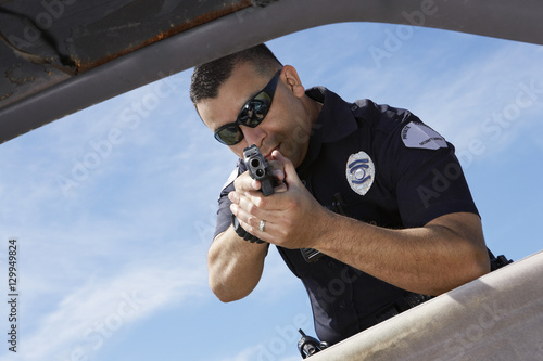 Caucasian male cop aiming with handgun against sky