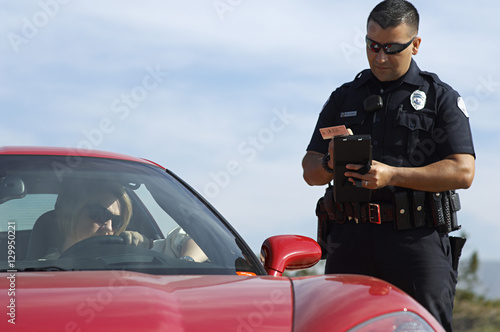 Traffic cop writing a ticket for woman sitting in sports car photo