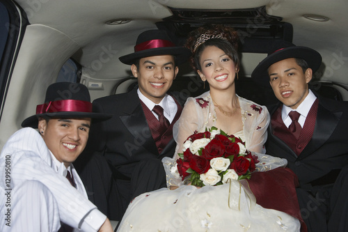 Portrait of a beautiful Quinceanera sitting with three male friends in Limousine photo