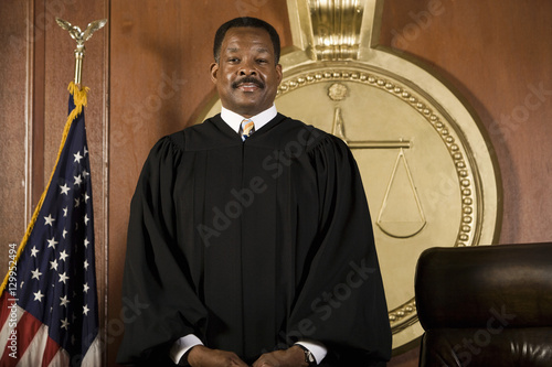 Fotografie Portrait of a happy male judge standing in courtroom