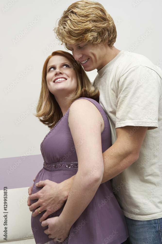 Happy young expectant couple looking at each other while embracing Happy young expectant couple looking at each other while embracing