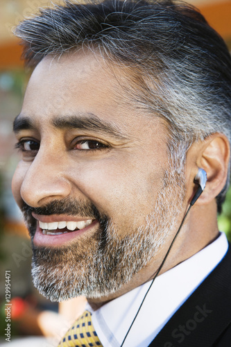 Closeup portrait of a happy Indian businessman listening music through earphone photo