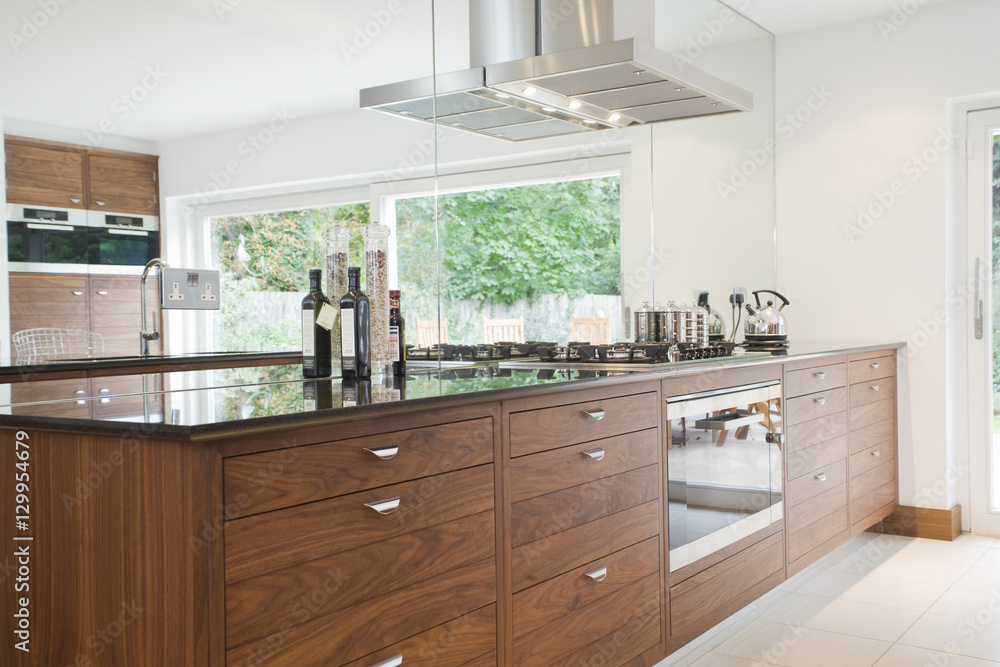 Fototapeta premium Bottles on countertop with wooden drawers in modern kitchen