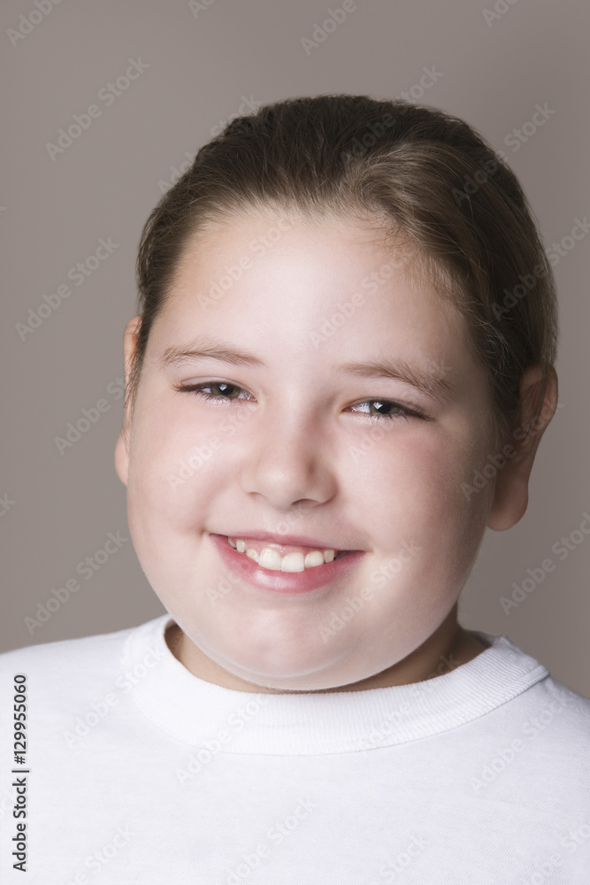 Closeup of an overweight girl smiling against gray background Closeup of an overweight girl smiling against gray background
