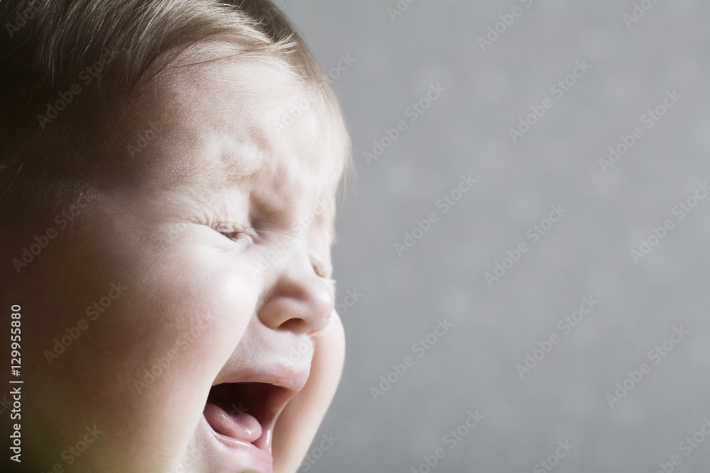 Closeup of a baby girl crying against gray background Closeup of a baby girl crying against gray background