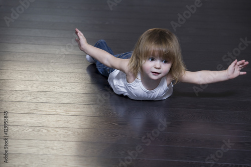 Fototapeta Naklejka Na Ścianę i Meble -  Little girl lying on floor and doing exercises
