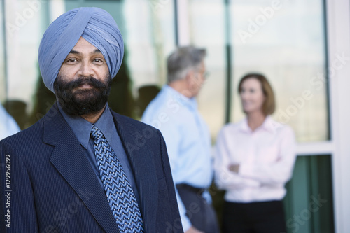 Photo Portrait of a confident Indian businessman with colleagues in the background