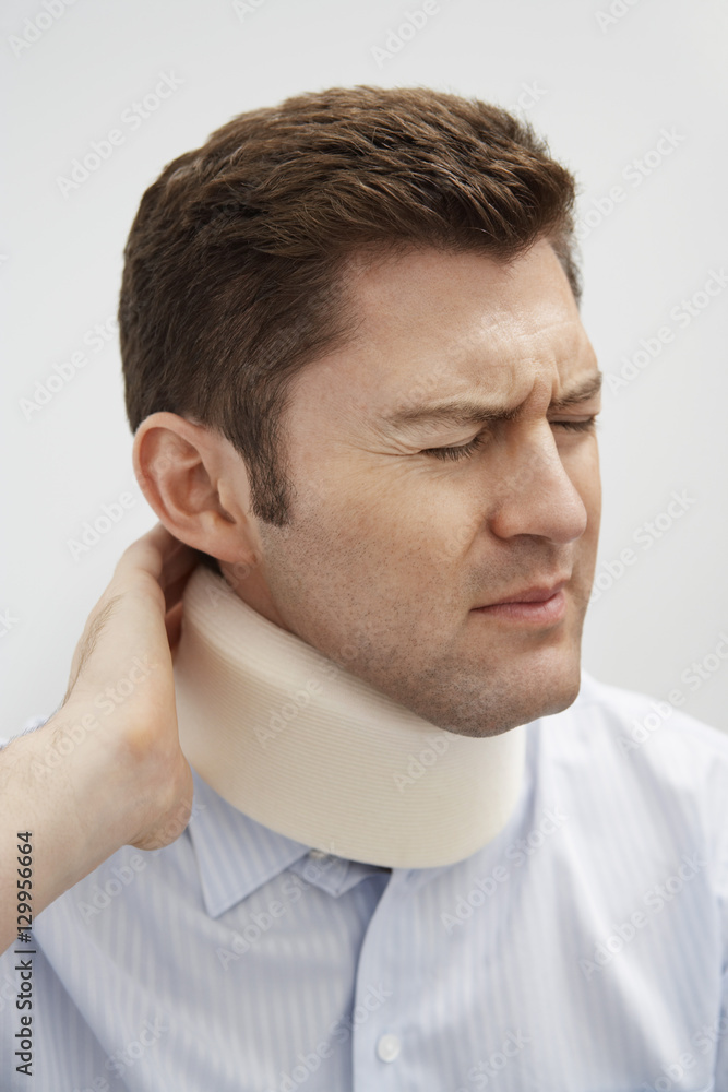 Closeup of a young male patient wearing neck brace having severe pain Closeup of a young male patient wearing neck brace having severe pain