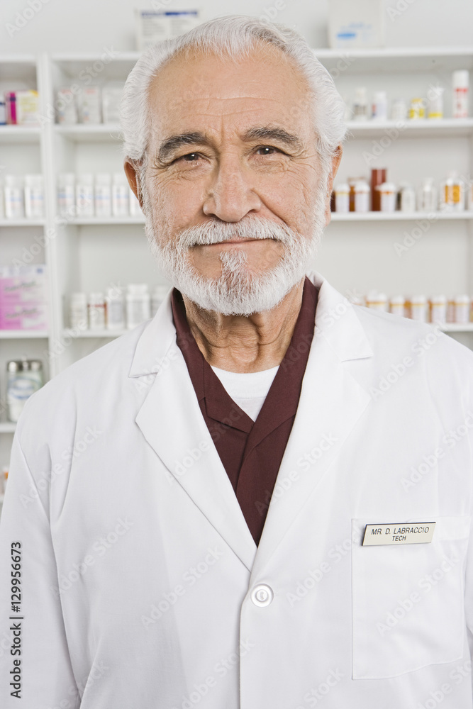 Portrait of a happy senior pharmacist in shop with medicines in the background Portrait of a happy senior pharmacist in shop with medicines in the background