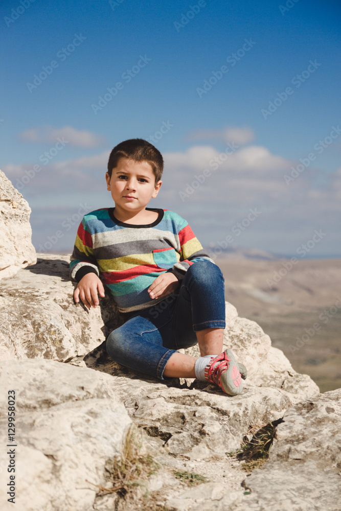 boy sits on the rocks over the valley