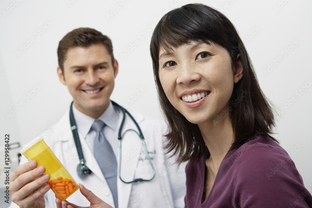 Portrait of happy doctor and patient holding tablet bottle in the clinic Portrait of happy doctor and patient holding tablet bottle in the clinic