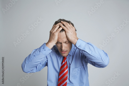 Depressed entrepreneur with hands on head isolated over grey background