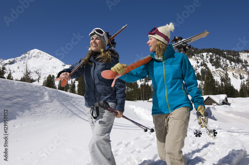 Happy female skiers carrying skis and snow boards on snowy landscape
