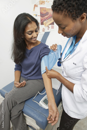 Female doctor checking happy Indian patient s blood pressure at the clinic
