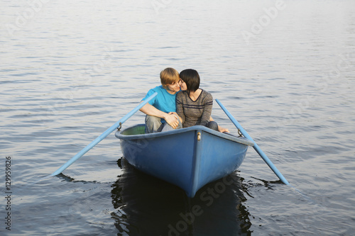 Canvas Print Loving young couple cuddling in rowboat at lake