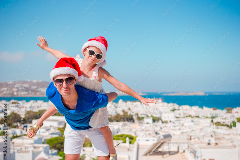 Obraz premium Little girl and happy dad in Santa Hats enjoy Christmas vacation with beautiful view