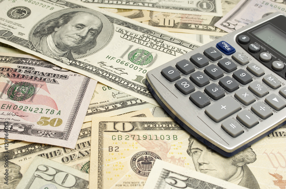 Calculator on heap of American dollar bills Calculator on heap of American dollar bills