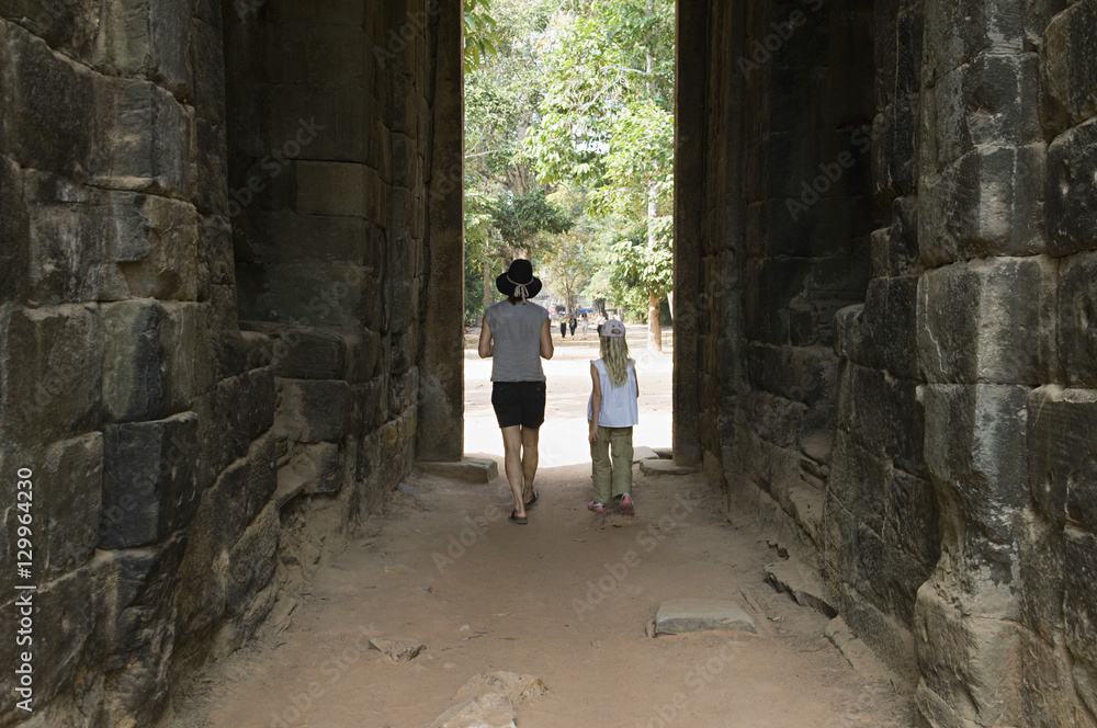 Full length rear view of mother and daughter walking through passage in ancient building