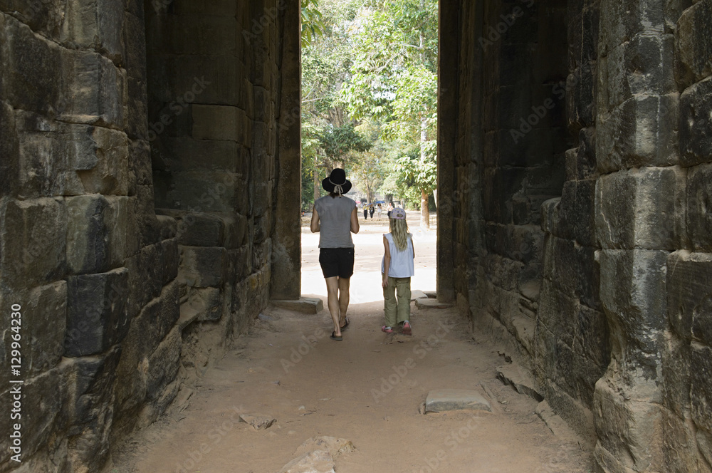 Full length rear view of mother and daughter walking through passage in ancient building Full length rear view of mother and daughter walking through passage in ancient building