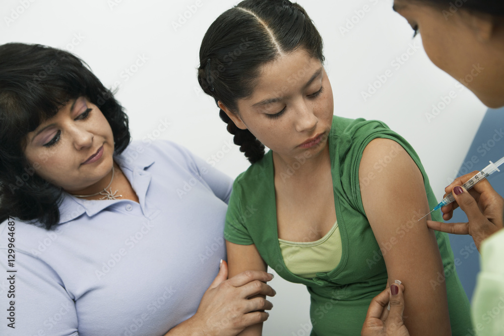 Teenage girl receiving an injection in the clinic Teenage girl receiving an injection in the clinic