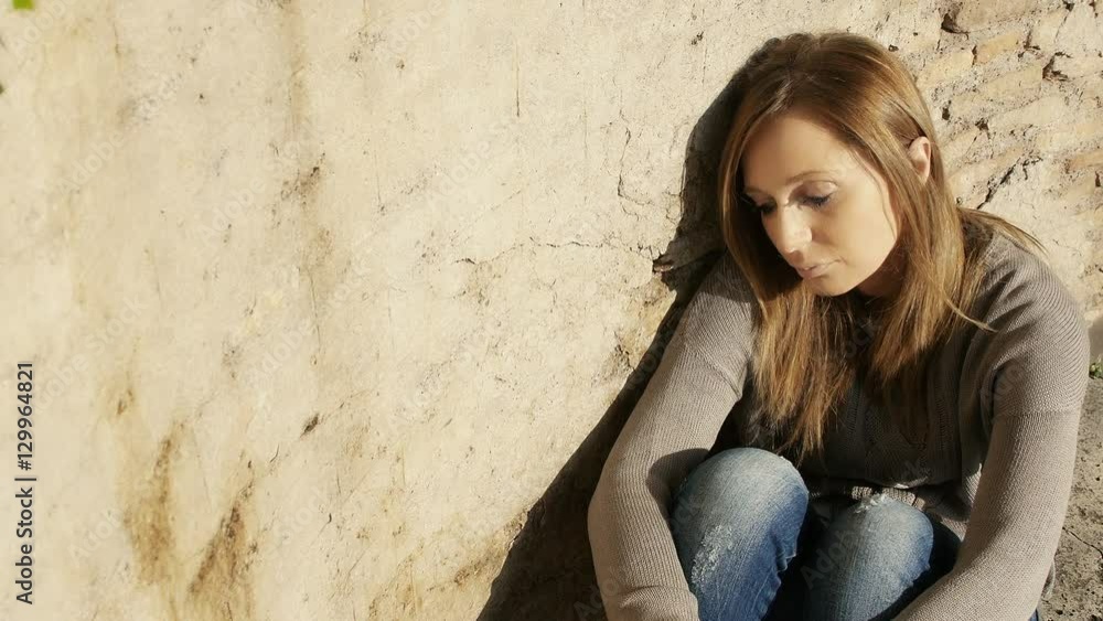 sad and depressed woman sitting on the ground against the wall sad and depressed woman sitting on the ground against the wall