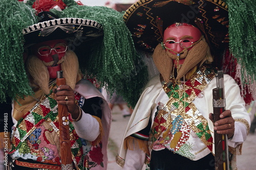 Portrait of two men wearing masks, costumes, sombreros and carrying guns, during the Huejotzingo Carnival in Mexico photo