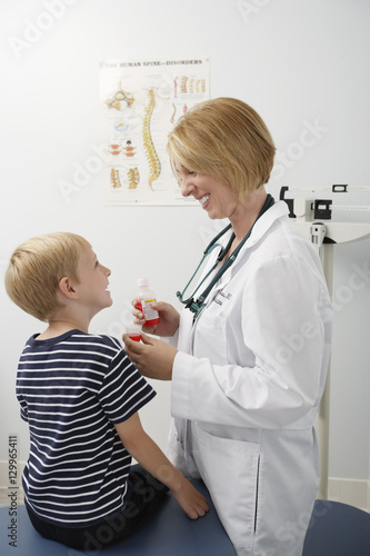 Happy female doctor giving medicine to a boy in the clinic