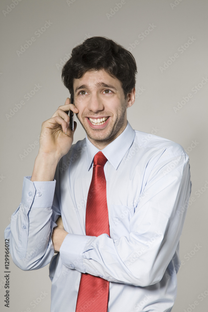 Happy young businessman using cell phone isolated over grey background Happy young businessman using cell phone isolated over grey background