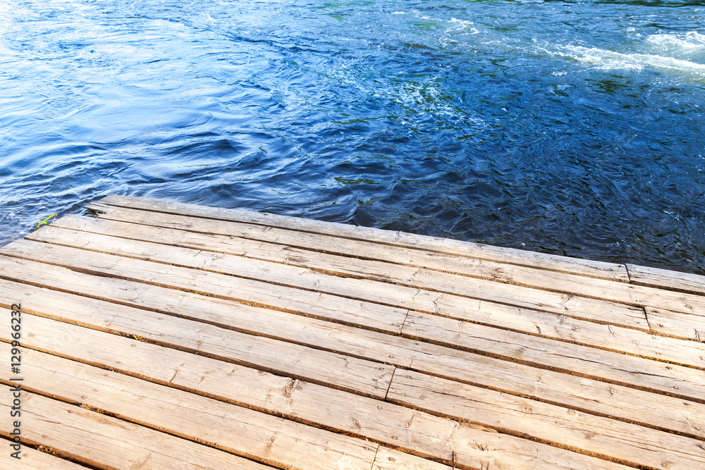 Corner of an old wooden pier with blue river Corner of an old wooden pier with blue river