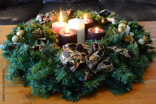 Traditional Advent wreath on rustic table with candles glowing warm