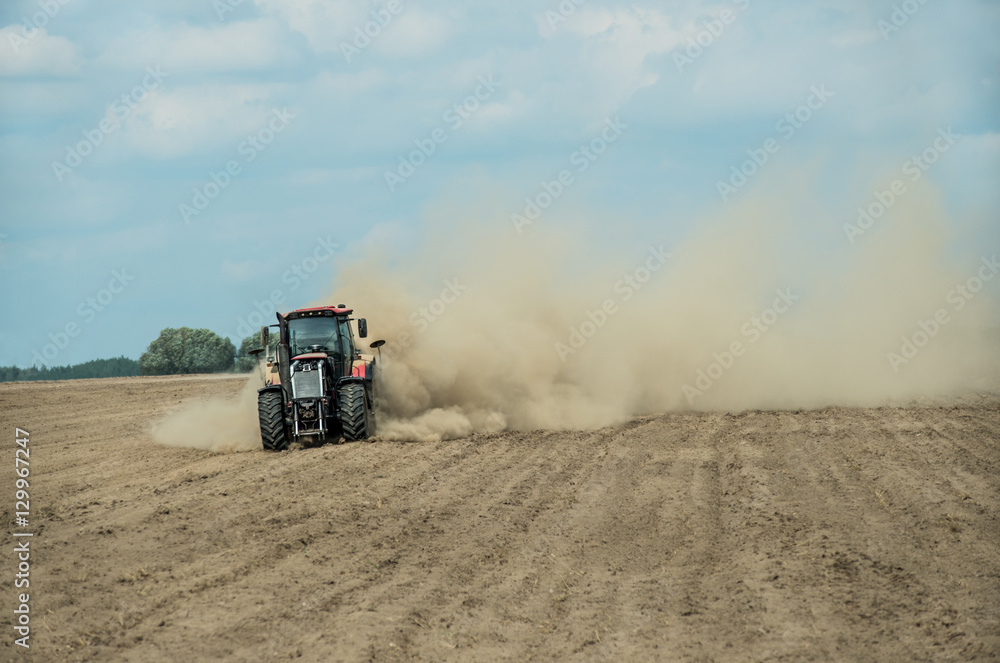 Naklejka premium Tractor plowing dry farm land at autumn