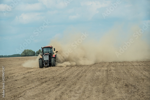 Tractor plowing dry farm land at autumn