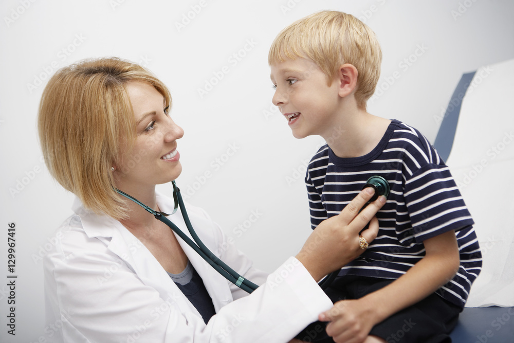Female doctor examining young boy with stethoscope in clinic Female doctor examining young boy with stethoscope in clinic