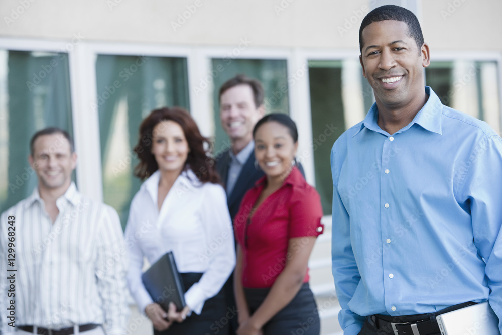 Portrait of an African American businessman with multiethnic executives in the background Portrait of an African American businessman with multiethnic executives in the background