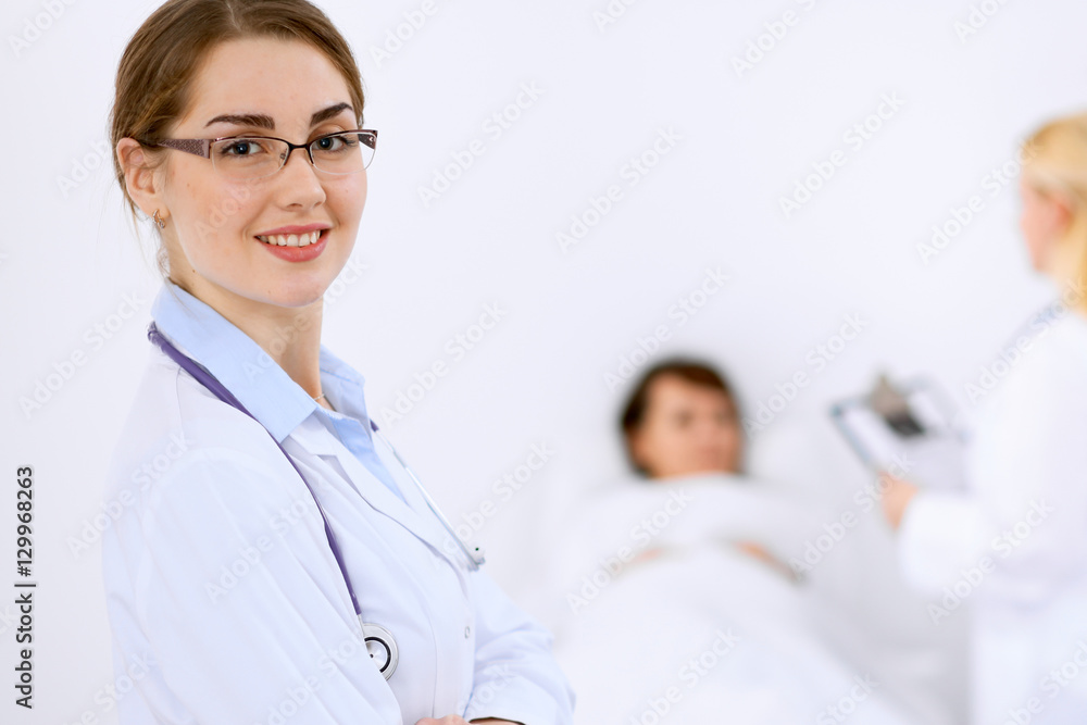 Female doctor smiling on the background with patient and his doctor Female doctor smiling on the background with patient and his doctor