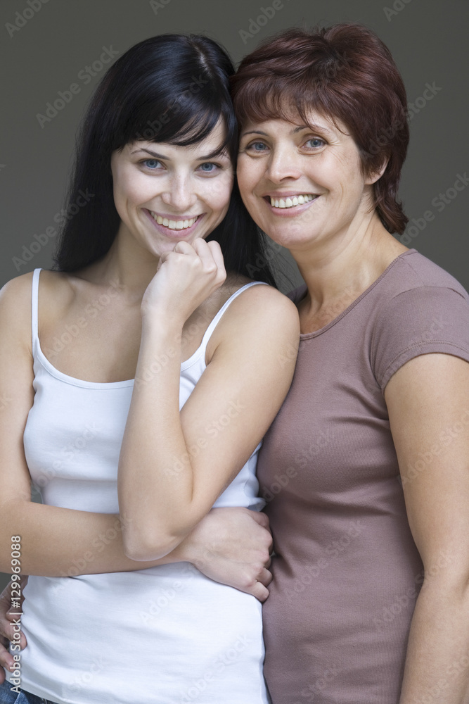 Portrait of a smiling young woman with her mother against gray background Portrait of a smiling young woman with her mother against gray background