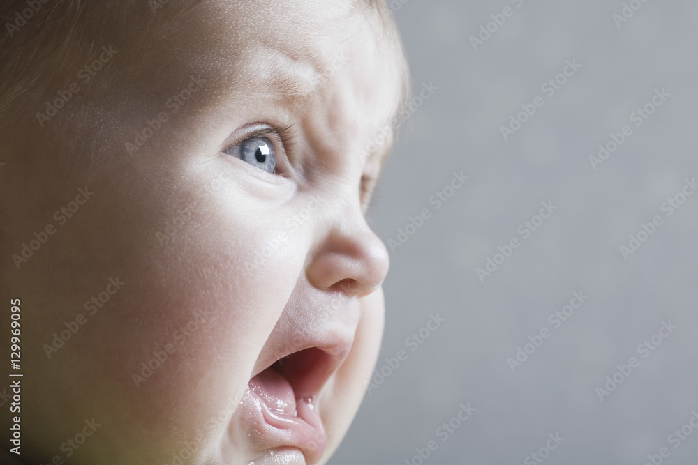 Closeup of a baby girl crying against gray background Closeup of a baby girl crying against gray background