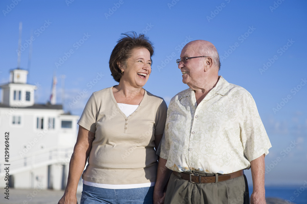 Happy romantic senior Caucasian couple looking at each other against clear blue sky
